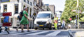 Voetgangers steken over bij een werkvak met een verkeersregelaar